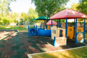 A playground with several different colored structures and some trees.