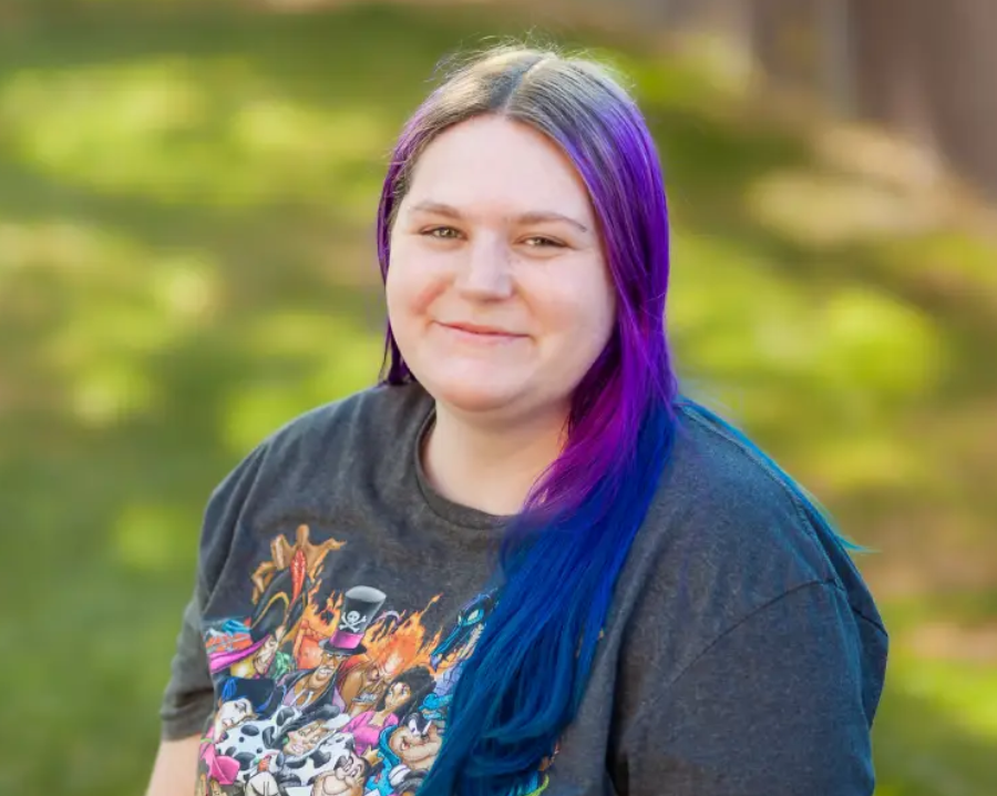 A woman with purple hair and a t-shirt.
