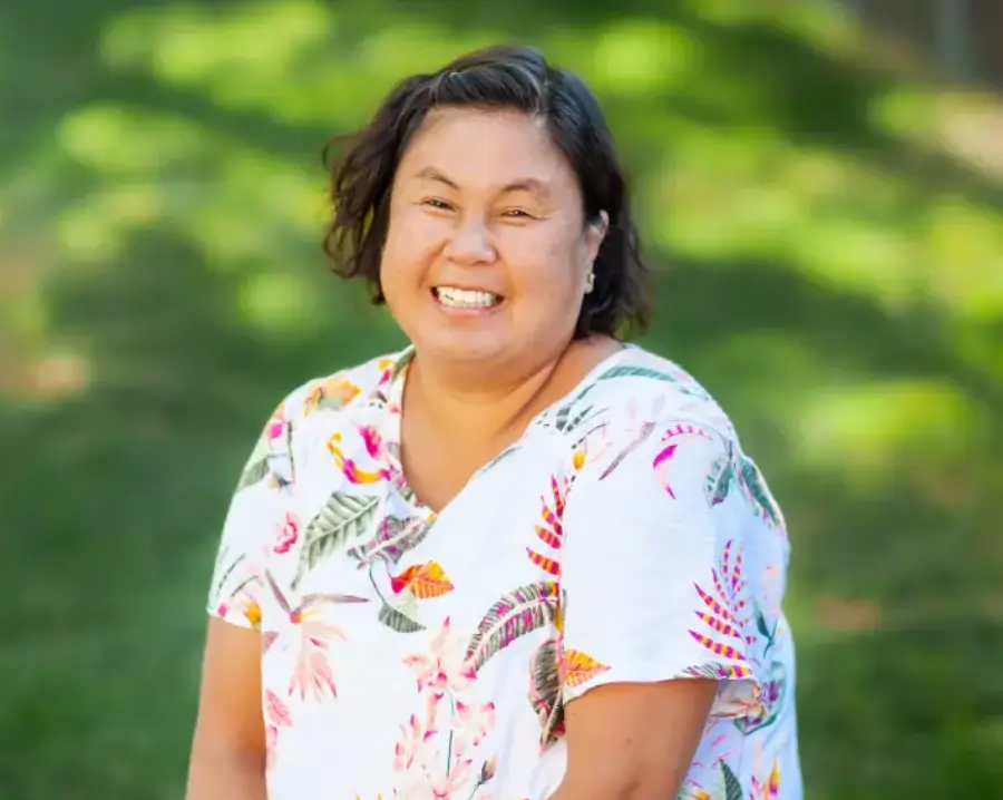 Untitled-design-39 A woman in floral shirt smiling for the camera.